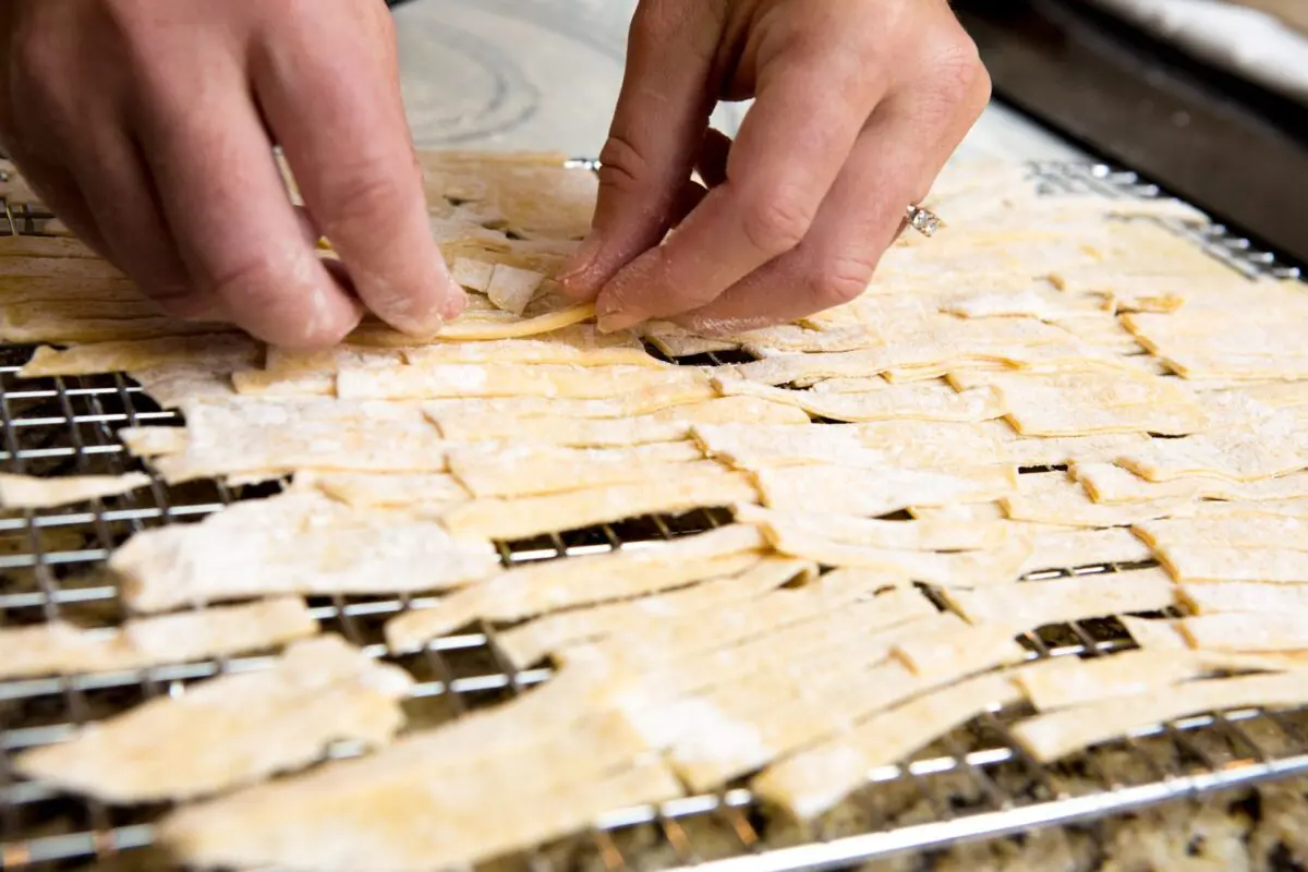 homemade egg noodles being placed on a cooking rack to dry