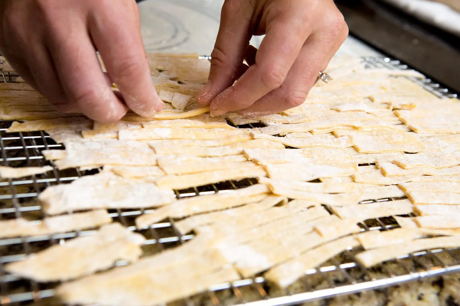 homemade egg noodles being placed on a cooking rack to dry