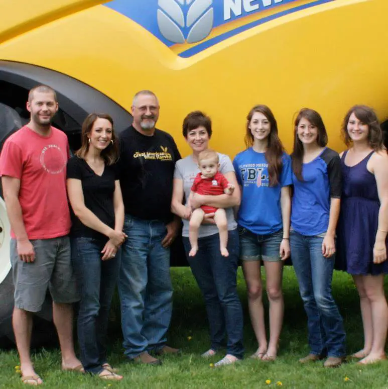 Happy farm family in front of combine.