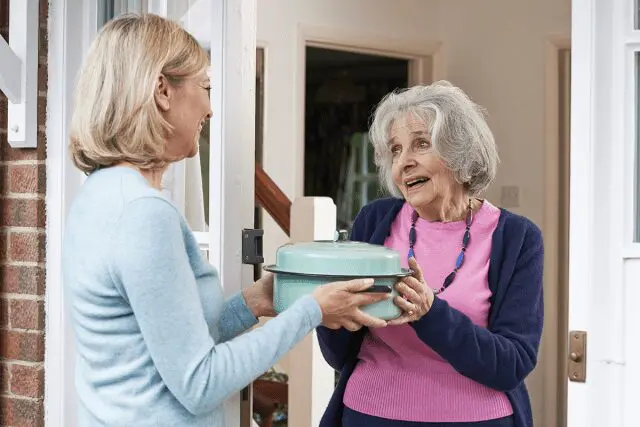 Photo: Woman delivering food to elderly neighbor.