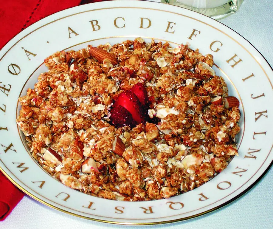 Granola Cereal in a white plate with the alphabet printed on the rim.