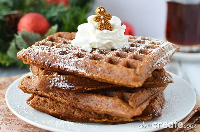 Gingerbread waffles on white plate with tiny gingerbread man on top. This is one of our unique waffle recipes