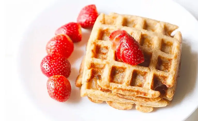 Whole Wheat Waffles on a white plate topped with strawberries