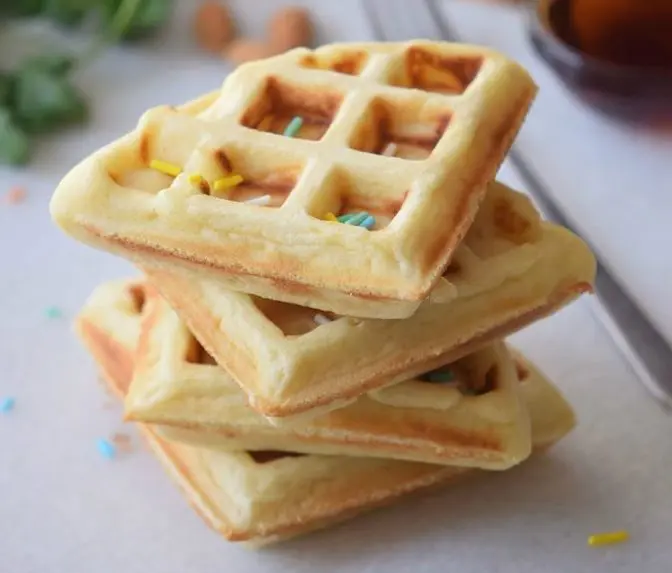 Cake waffles topped with sprinkles on a white cutting board