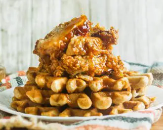 Fried chicken on top of waffles being drizzled with maple syrup. This is one of our unique waffle recipes