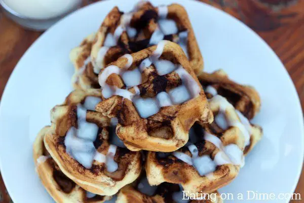 Cinnamon Roll Waffles drizzled with frosting on a white plate. One of our 18 unique waffle recipes