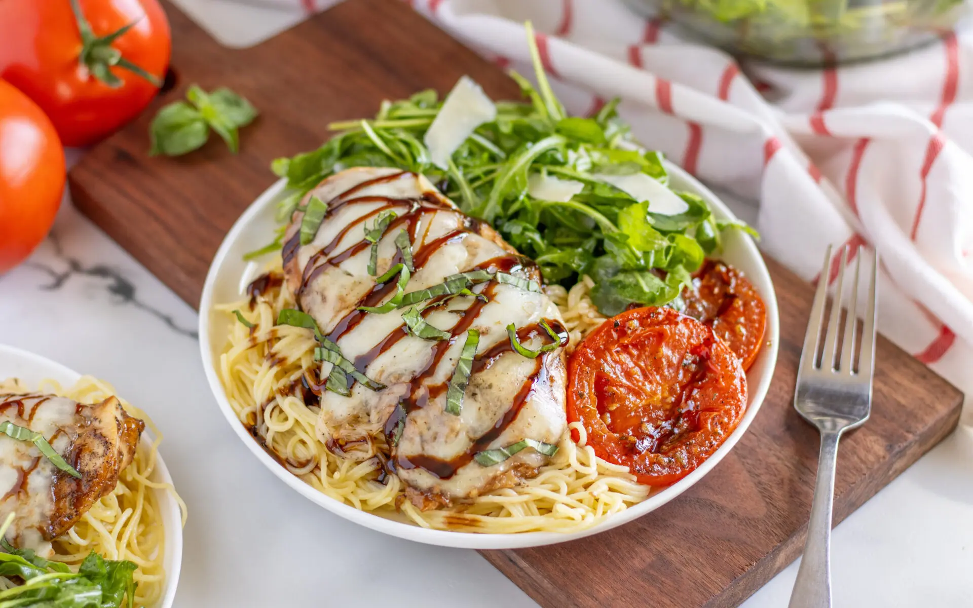 Caprese Chicken Dinner Web 2 | Eat Wheat Shows Caprese Chicken Dinner plated in a bowl, set on a table.