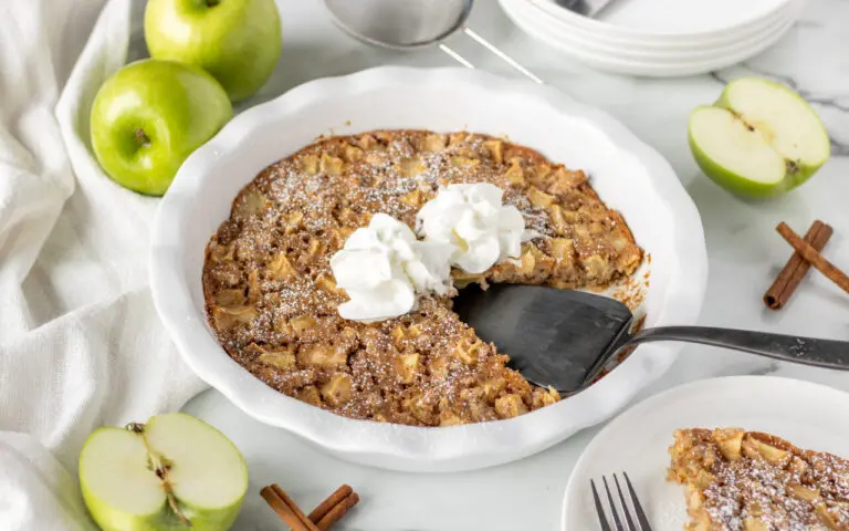 Swedish Apple Pie in a white pan with a serving spoon inside the dish.