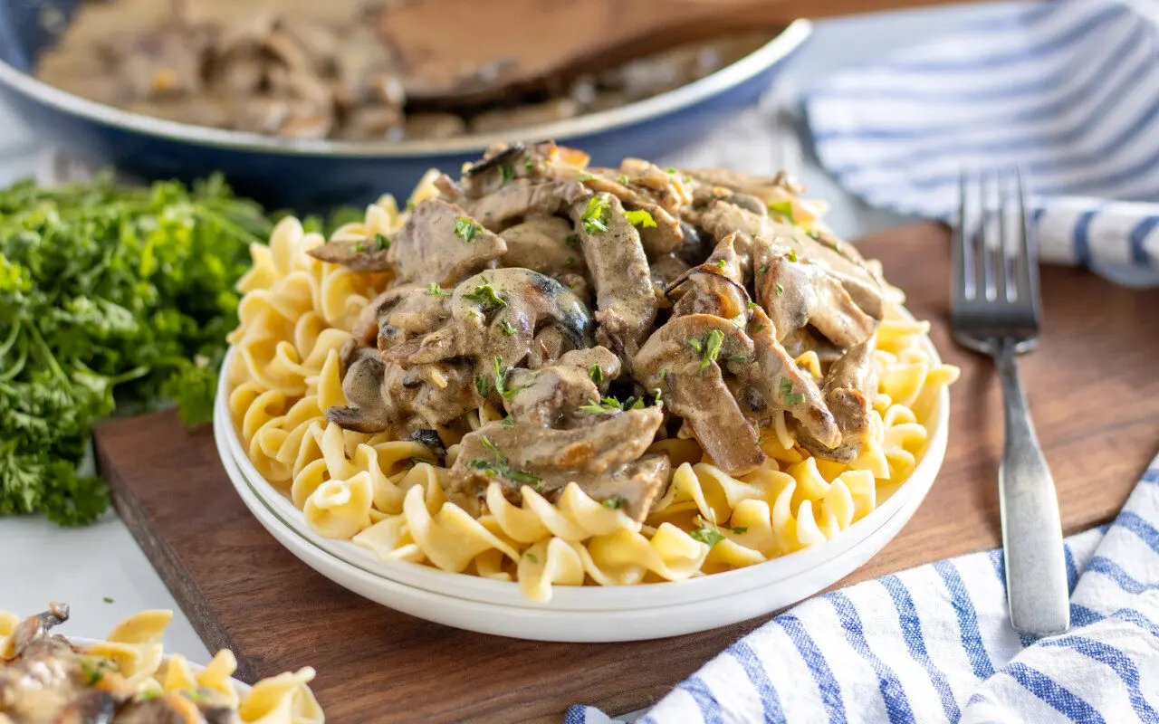 Beef Stroganoff in a bowl with a fork laying beside it.