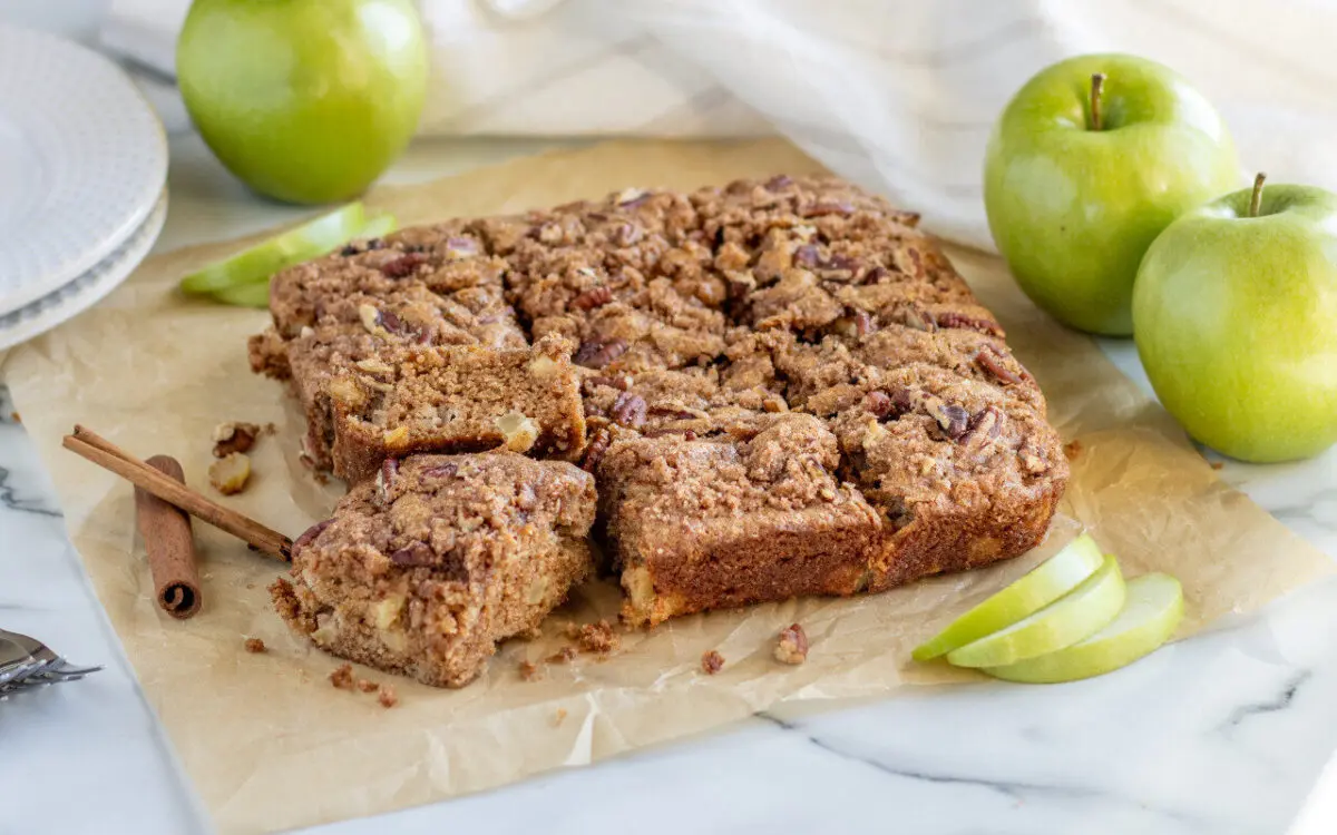 Whole Wheat Apple Cinnamon Cake sliced into bars with apples in the background.