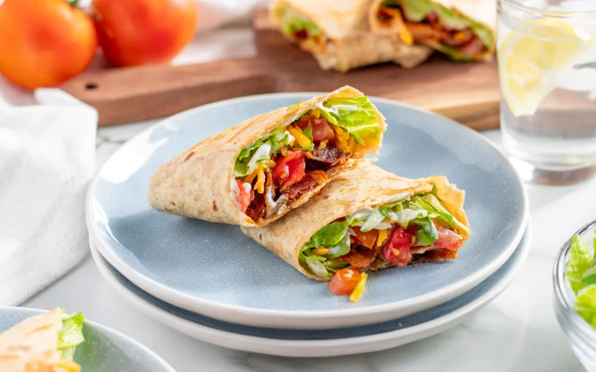 Toasted BLT Wraps cut in half on a serving plate.