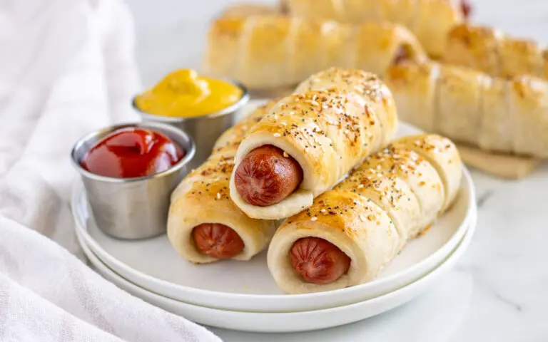 Full Size Pigs in a Banket stacked on a plate with dipping sauce on the side.