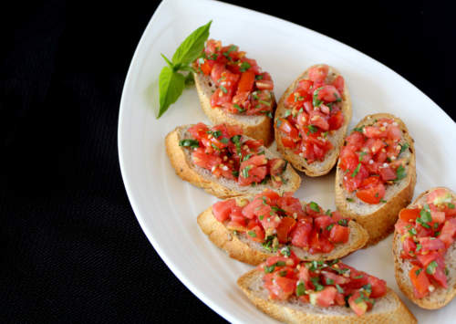 Bruschetta on an oblong plate with a black background. This quick-and-easy bruchetta recipe is sure to be a family favorite.
