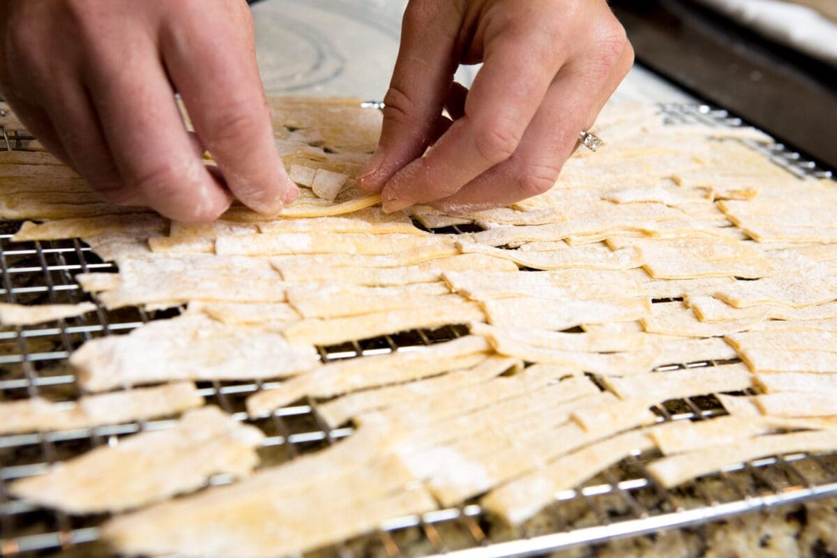 homemade egg noodles being placed on a cooking rack to dry