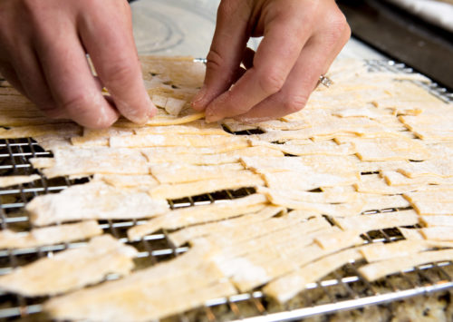 homemade egg noodles being placed on a cooking rack to dry