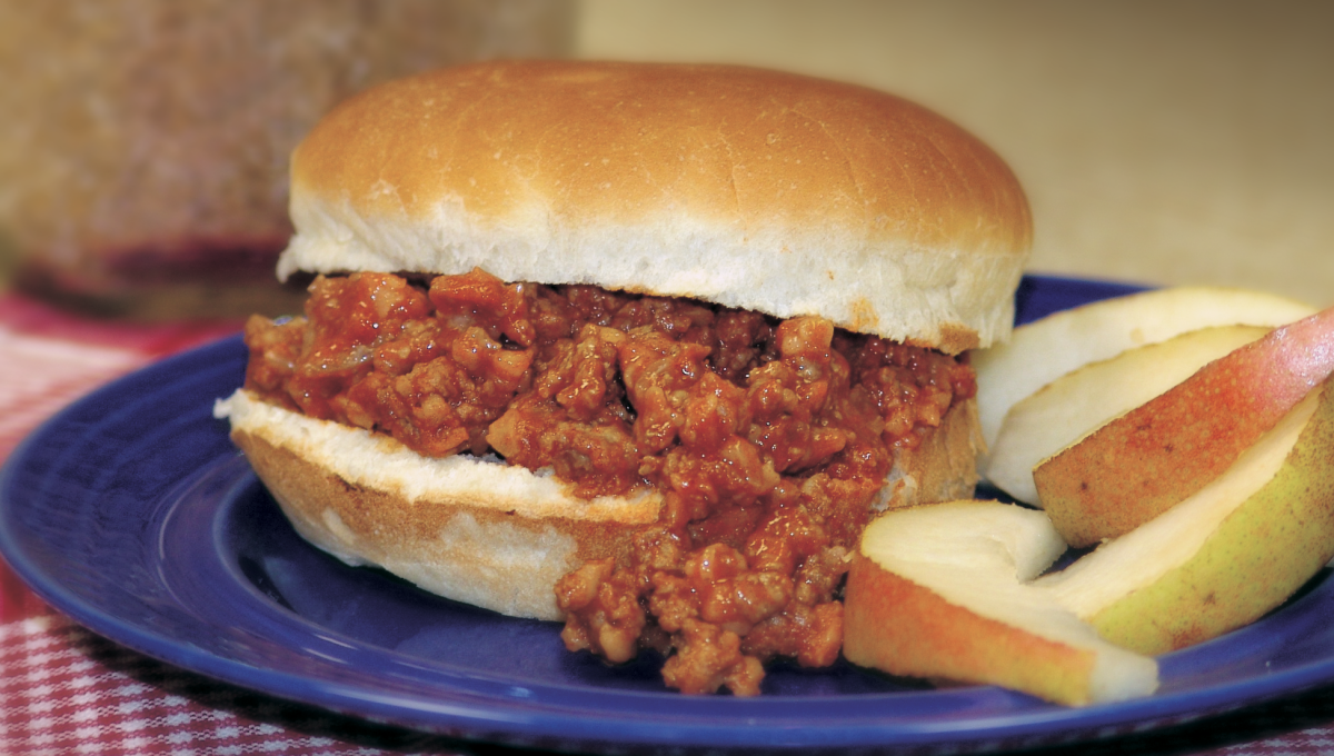 Sloppy Joes served with apples on a plate with a checkered table cloth
