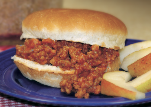 Sloppy Joes served with apples on a plate with a checkered table cloth