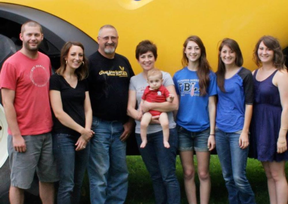 Happy farm family in front of combine.