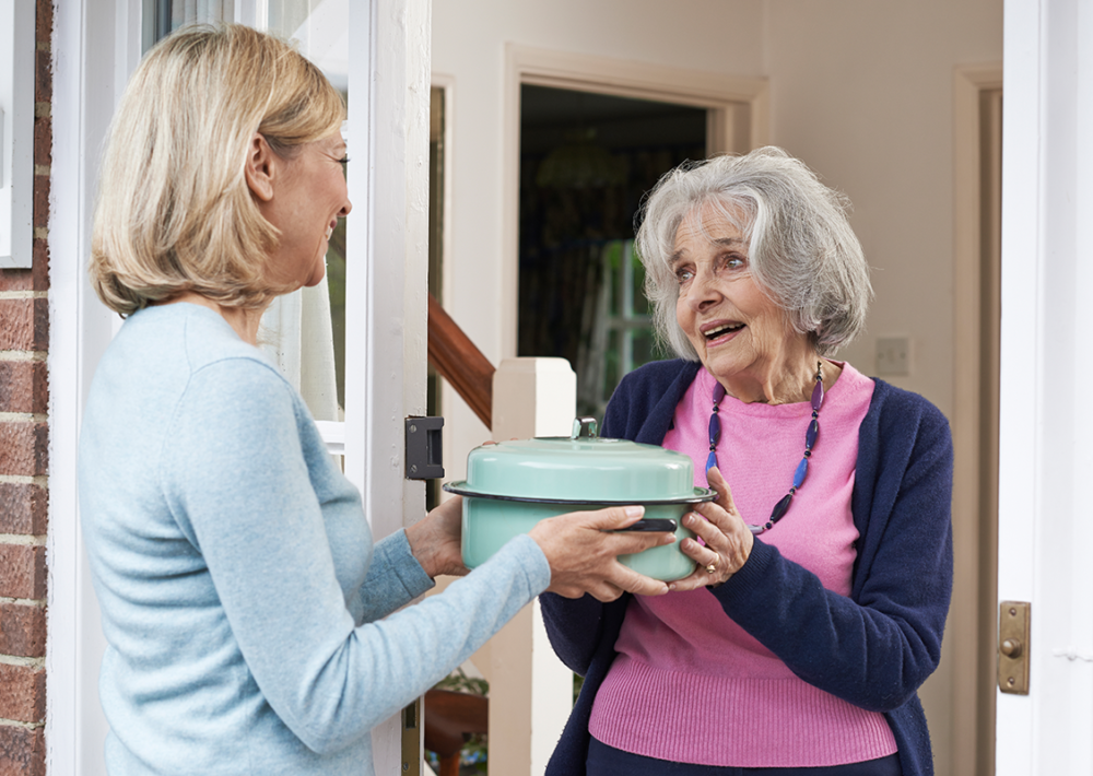 Photo: Woman delivering food to elderly neighbor.