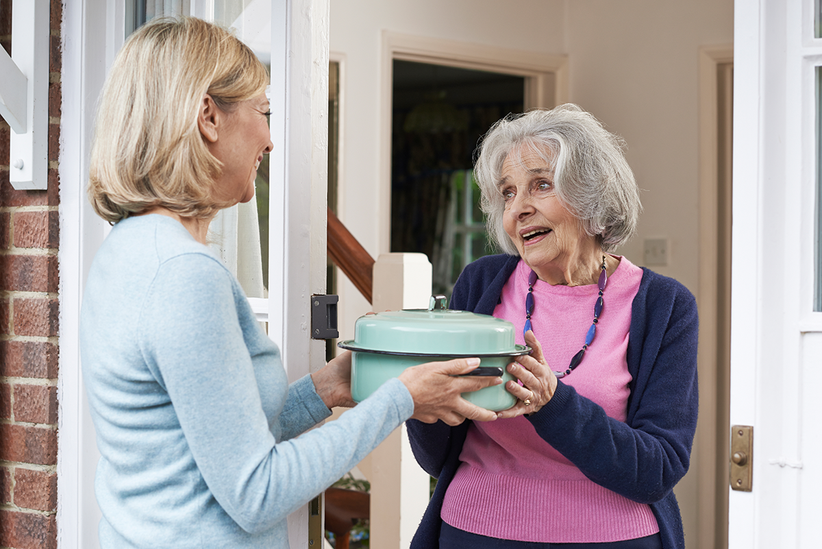 Photo: Woman delivering food to elderly neighbor.