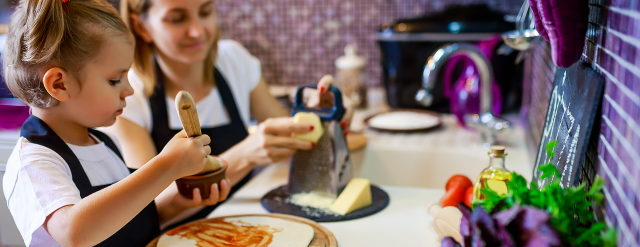 Photo: Mom and daughter cooking pizza in kitchen.