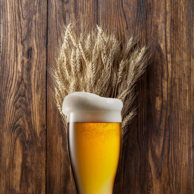 Wheat beer in front of wheat and wood background