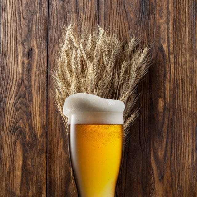 Wheat beer in front of wheat and wood background