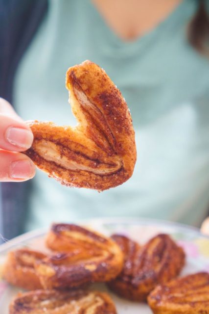 Cinnamon and Sugar Puff Pastry Palmiers being held by woman.