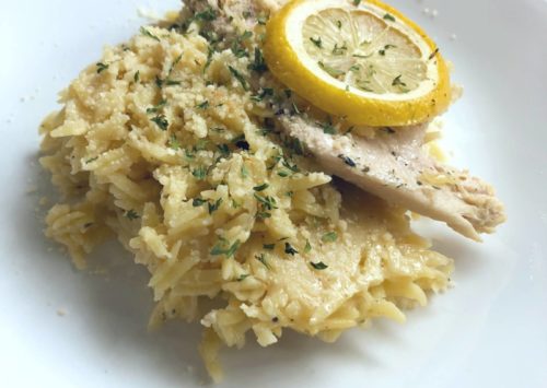 Lemon Orzo Chicken Bake on a white dish served with a lemon slice.